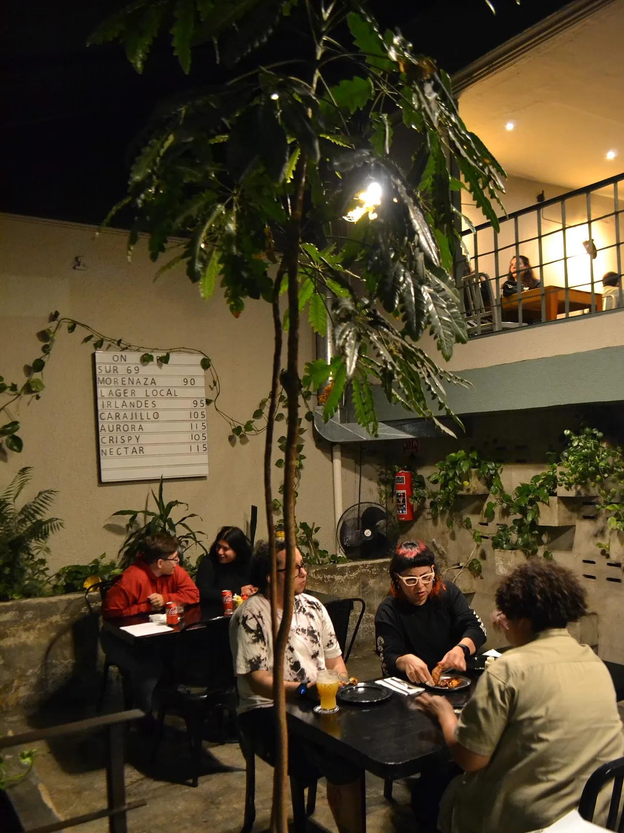 Amigos reunidos en Pig’s Pearls entre vegetación, madera y luces cálidas